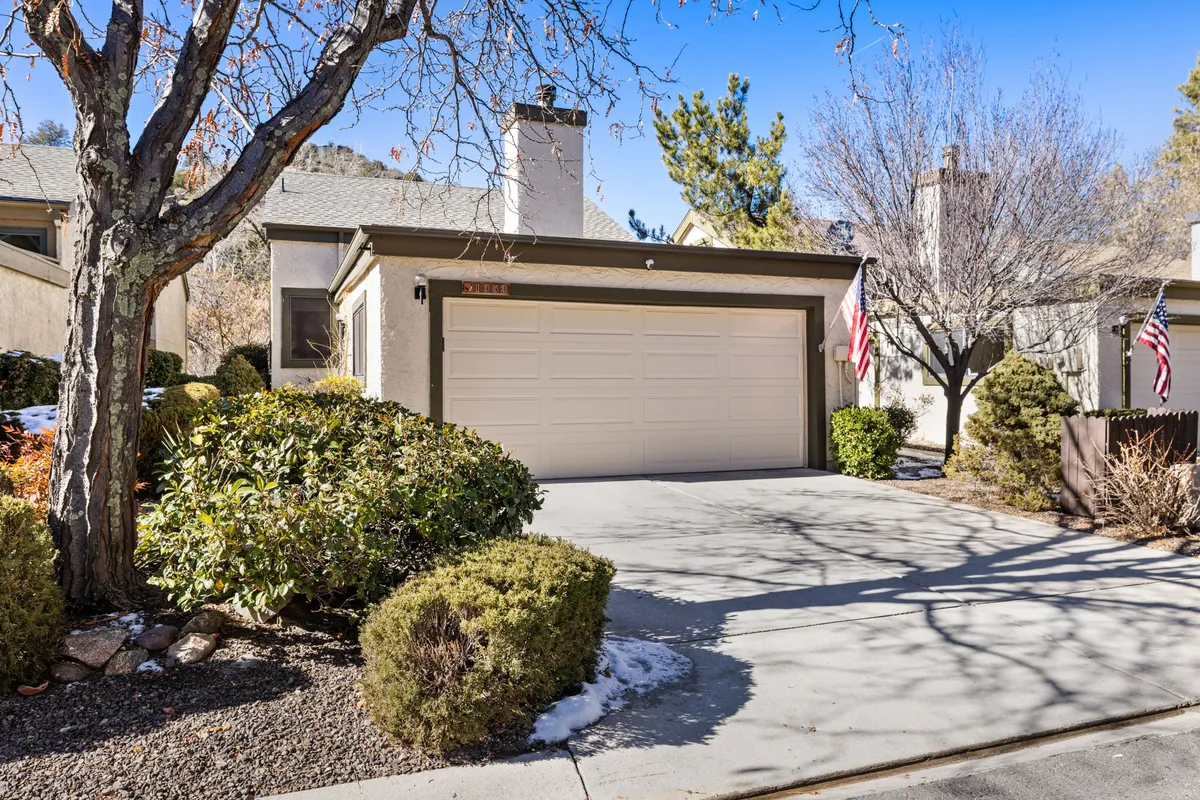 The photo captures a well-maintained front yard with decorative bushes, garage door, and flagpoles, radiating a sense of community and outdoor enjoyment. The space hints at the possibility of summer barbecues, neighborhood walks, and outdoor family gatherings.