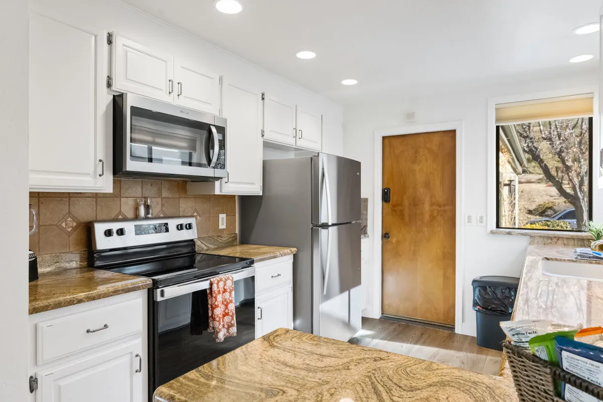 A functional kitchen featuring a central island, gleaming granite countertops, stainless steel appliances, and abundant natural light. The layout encourages meal preparation and group participation, with enough space for several people to gather and cook together.