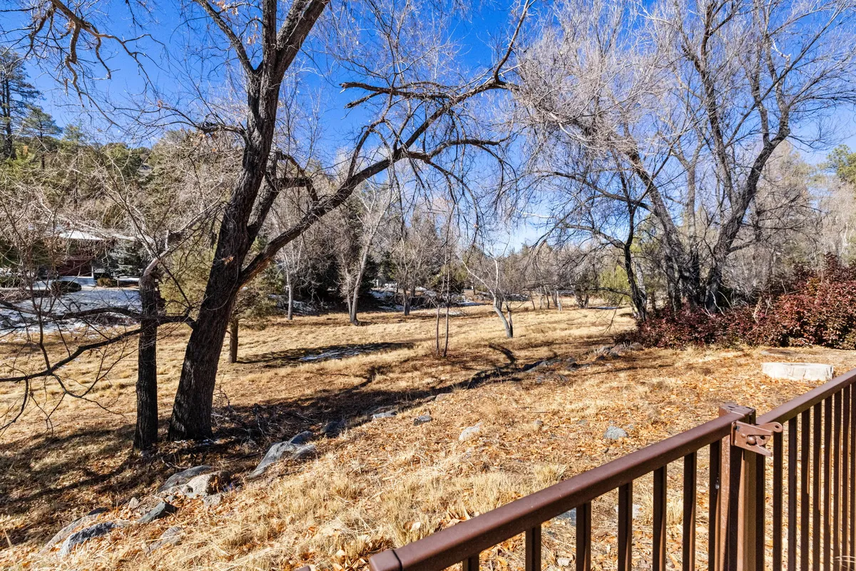 This image captures a large, open backyard bordered by bare trees and a fenced area, with distant structures visible beyond the field. The expansive, natural setting emphasizes a direct connection to the outdoors, making it ideal for starting hikes, bike rides, or enjoying evening stargazing. The open space is versatile, accommodating various outdoor activities and gatherings.