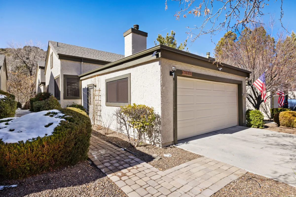 A welcoming exterior view of the home, featuring the front door, garage, landscaped bushes, and American flags. The scene suggests a family-friendly environment and hints at outdoor gatherings or relaxation on the porch.